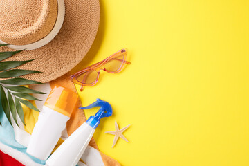 Flat lay of sunscreen, hat, and sunglasses on a bright yellow background, ideal for sun safety...