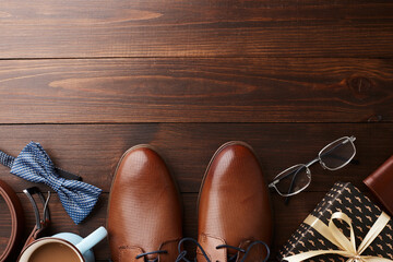 Top view of Father's Day essentials with blue accents, including shoes, tie, and a gift on wooden backdrop, ideal for articles or promotions on how to celebrate dads