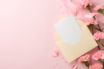 Elegant flat lay of a pastel pink envelope with a blank card, surrounded by soft pink carnations and ribbon, ideal for Mother's Day, wedding, or Valentine's Day themed promotions