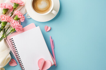 Beautifully arranged desk featuring coffee, a notebook, and pink carnations, ideal for themes related to work from home, creativity, or spring