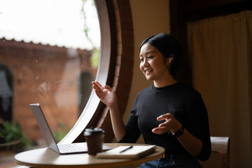 A woman is sitting at a table with a laptop and a cup of coffee