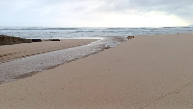Landscape view of sea sand, moss and coral rocks on a cloudy summer day. Molang Beach, Tulungagung, Indonesia