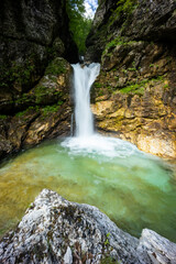 Fototapeta premium Rio di Repepeit. Wonderful waterfall that falls from a cliff. The force of the waterfall is a sight to behold. Hiking, trekking in the open area surrounded by woods. Summer holidays, peace.