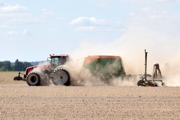 Fototapeta premium Agriculture. A modern tractor sows seeds with a multifunctional seeder 