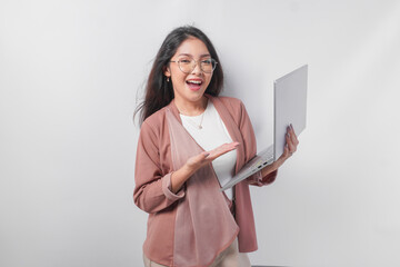 Smiling young Asian business woman pointing to the laptop she holds on isolated white background.