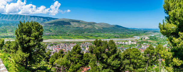 A panorama view past trees from the castle overlooking the northern side of Berat, Albania in...