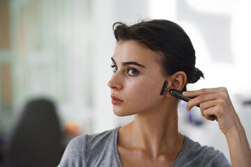 A young woman massages her face with gouache while looking in the mirror.