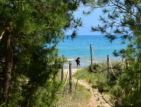 signora che che cammina in acqua nella spiaggia selvaggia durante i primi giorni di estate 