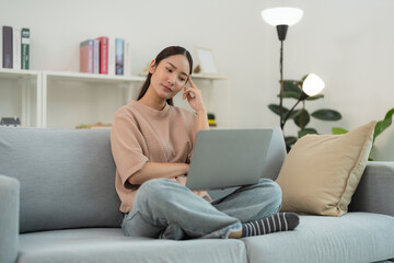 Thoughtful young woman working on laptop at home