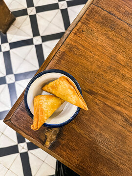 Two samosas in a bowl on a table (Mumbai, India)