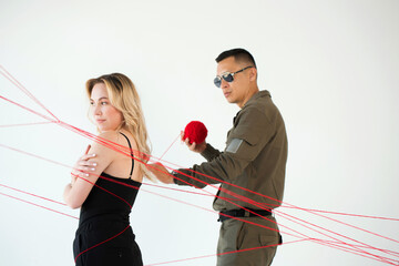 A man wraps red threads around a woman