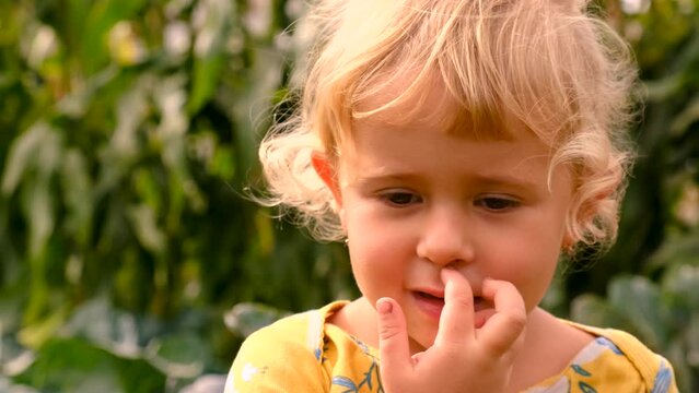 A child picks his nose in the park. Selective focus.