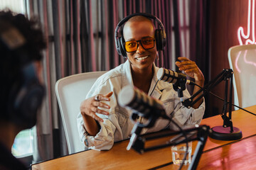 Happy young woman recording podcast with co-host in modern studio