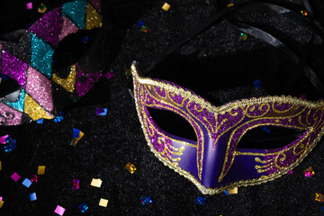 Masquerade mask with confetties on black background.