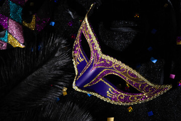 Close-up view of Masquerade mask with confetties on black background.