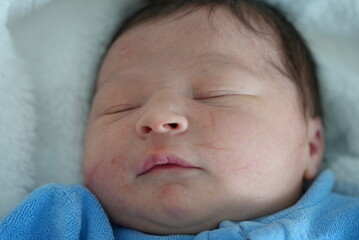A serene close-up of a newborn baby’s face, peacefully sleeping, highlighting the delicate...