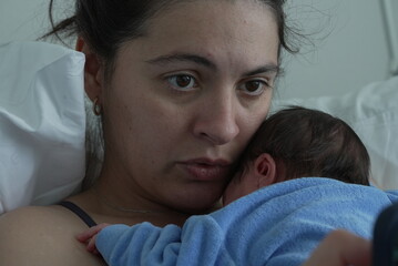 Close-up of a mother and her newborn in the hospital, showing a quiet and intimate moment of...