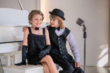 Two children dressed in black and white in front of a piano.