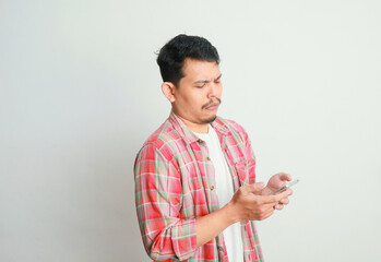 Asian man holding his mobile phone with sad expression.