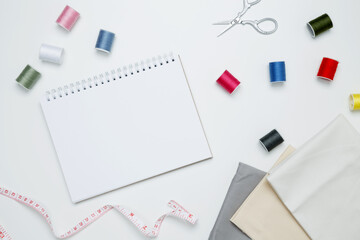 Composition with various threads and sewing accessories on white background. Mock up notebook