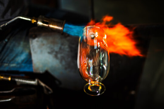 Fire hits a glass decanter in glass blowing workshop. Motion blurred.