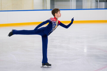 A young boy is skating on ice with his arms outstretched.