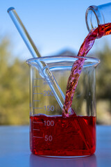 Pouring red chemical liquid in a recipient
