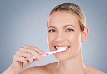 Woman, portrait and brushing teeth in studio for dental care, oral hygiene and fresh breath. Female model, toothbrush and wellness with smile, happiness and confidence or pride by gray background