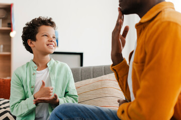 Smiling, positive African American little boy and his dad communicating with sign language - Powered by Adobe