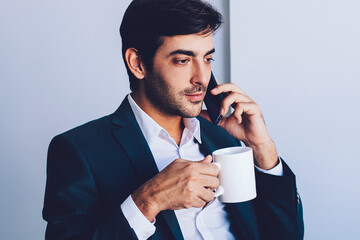 Serious indian businessman enjoying coffee break after work in company office calling to colleague...