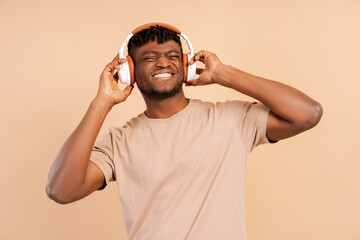 Attractive african young hipster man wearing wireless headphones listening to music