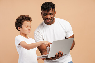 Positive, smiling, handsome African American man, father and his little cute son, using laptop