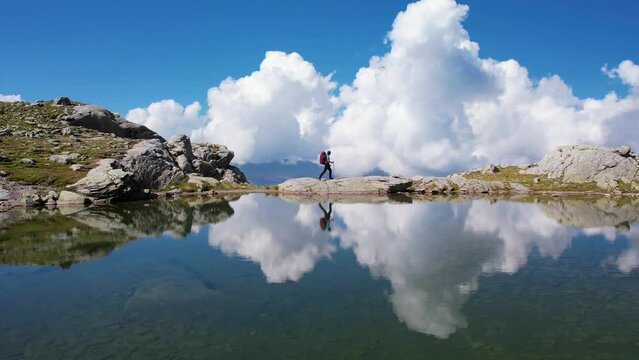 Aerial view to sporty woman with backpack hiking near lake on mountain top in Grindelwald valley Swiss alps enjoying sunny day