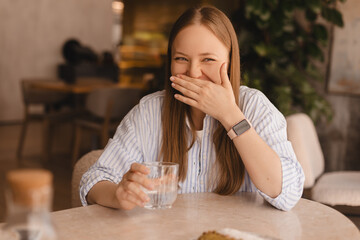 Delighted girl sitting in the cafe hold and drink glass of water resting in restaurant. Food,...