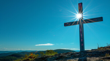 A Christian cross on a high plateau during a clear day, with the unobstructed sun illuminating the cross and the bright blue sky providing a vivid canvas behind it.
