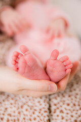 A mother holds her newborn infant baby daughter's feet in her hands. 