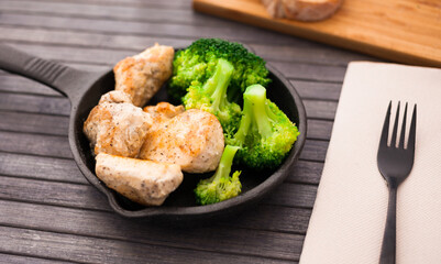 healthy appetizer of chicken pieces with broccol in small cast iron skillet