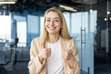 Smiling businesswoman giving thumbs up at the office