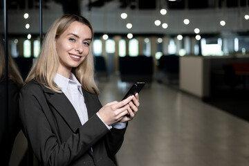 Smiling businesswoman using smartphone in modern office setting