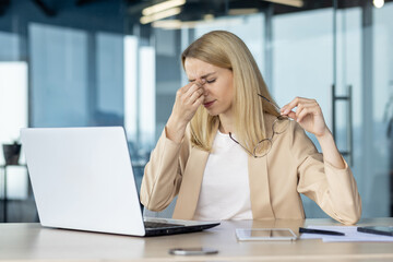 Stressed businesswoman experiencing fatigue while working on laptop in modern office