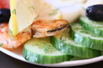 Fresh cucumbers and succulent shrimp on a white plate, perfect for seafood lovers