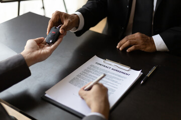 Customer signing car purchase or lease contract agreement with car salesman, car insurance.