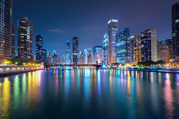 A glistening city skyline illuminated against the night sky, with dazzling lights reflecting in the calm waters of an urban river.