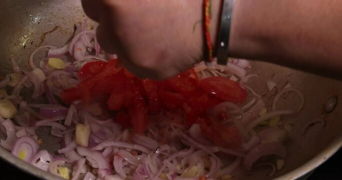 Saut&eacute; frying tossing squeezing tomato onion garlic cumin red dry chilli spice in hot oil saucepan cooking for dal tadka bagar 