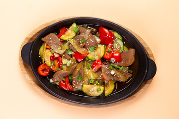 Fried beef tongue with vegetables in a plate.