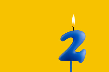 Blue birthday candle on yellow background - Number 2