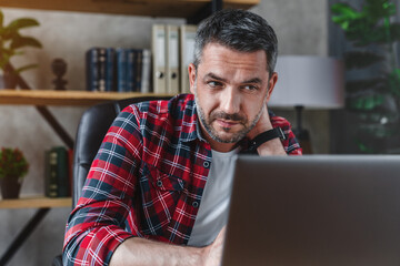 Caucasian man office worker freelancer touching neck due to tiredness from remote work on laptop...
