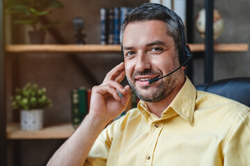 Portrait of caucasian customer support manager worker in headset working with laptop computer in...