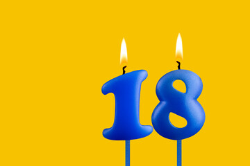 Blue birthday candle on yellow background - Number 18