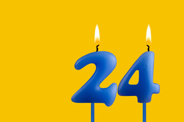 Blue birthday candle on yellow background - Number 24